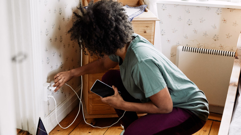 Person crouching awkwardly to plug in a phone