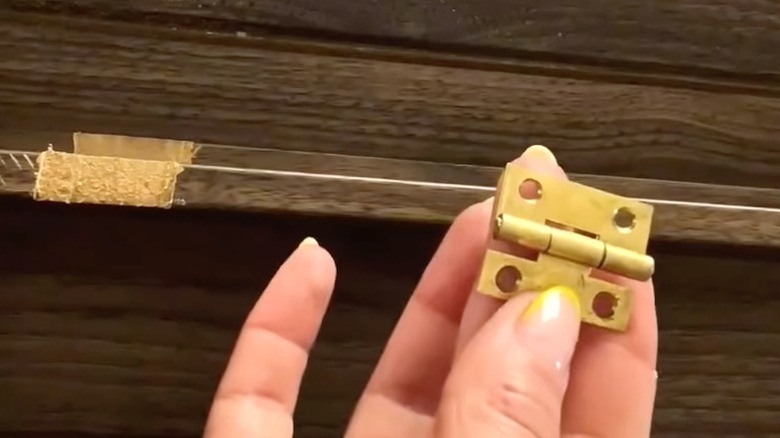 Person preparing the shelf for attaching a hinge