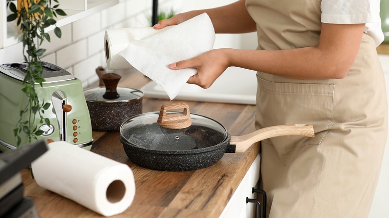 woman cleaning with two rolls of paper towels taking up counter space