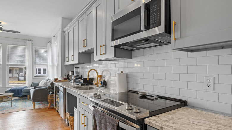 Modern kitchen with sleek stainless steel appliances, countertops, and wooden flooring.
