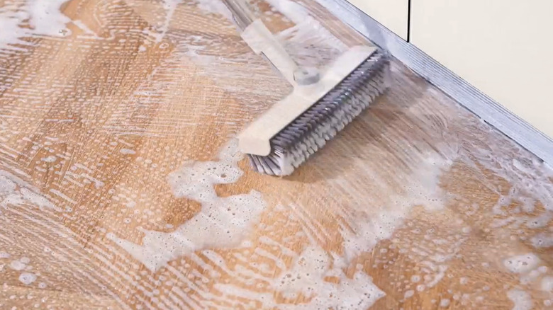 Broom scrubbing wooden floor