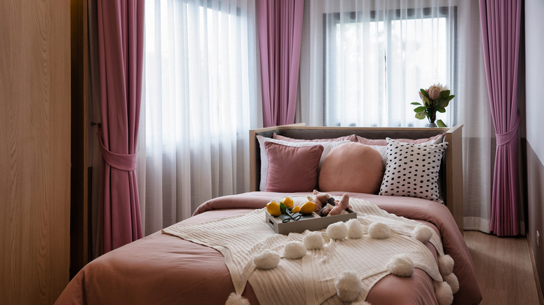 Long, pleated pink and white curtains in a bedroom