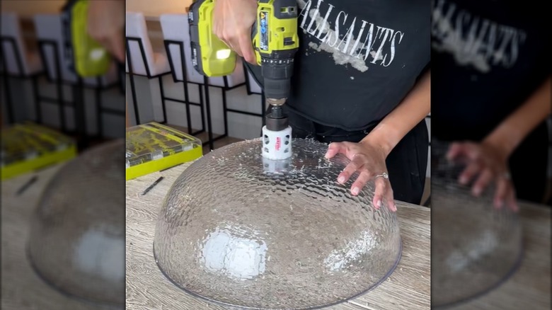 A crafter makes a hole in a plastic bowl with a heavy duty drill bit.