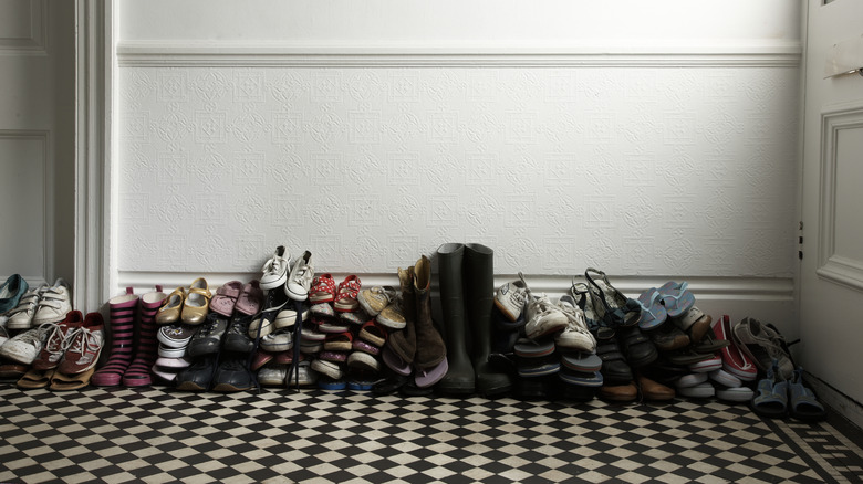 A pile of shoes stacked in entryway by front door