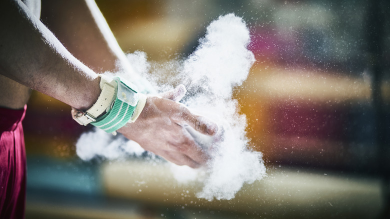 Powdery chalk scatters into a cloud as it's clapped between a pair of hands.