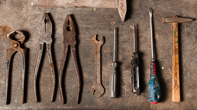 A collection of rusty tools laid out on a workbench