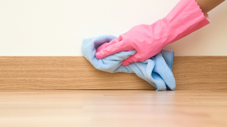 Woman with gloves cleaning baseboards