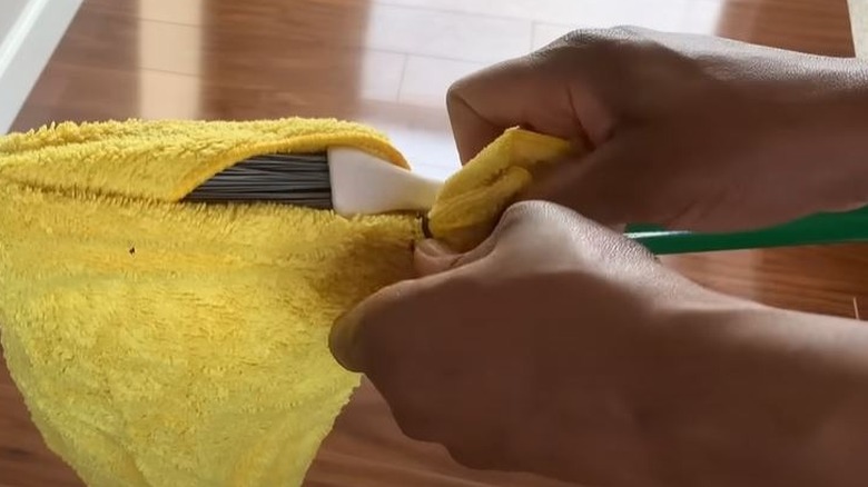 Woman putting cloth over broom for DIY baseboard cleaning hack