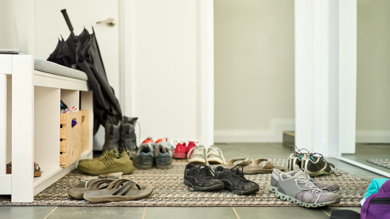 Multiple pairs of shoes on a floor rug, with no organization