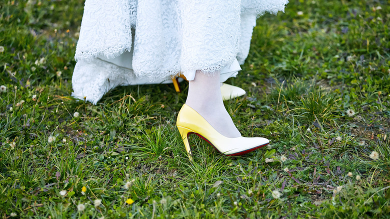 A woman wearing high heels stands in a grassy yard