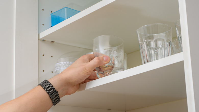 Close up of person grabbing cup from shelf