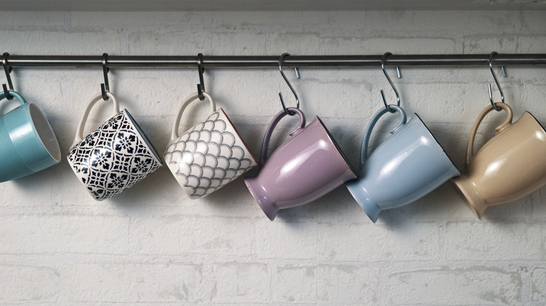 Mugs hanging from S-hooks on a bar