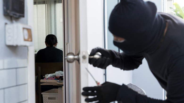 Masked burglar breaking into a house