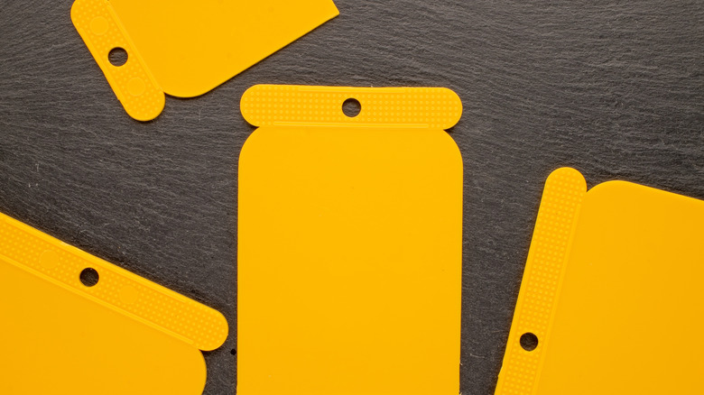 Yellow plastic paint scrapers on a black surface