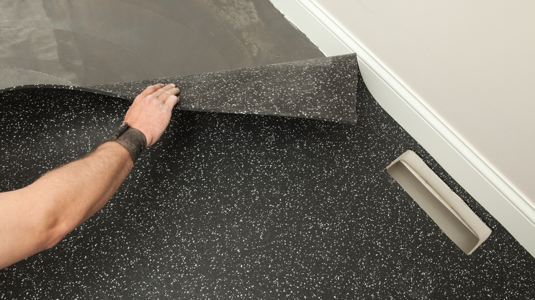 Person installing rubber floor over concrete subfloor