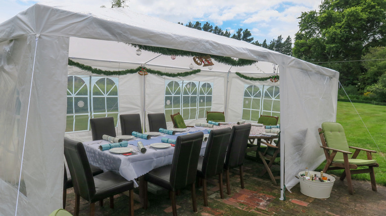 Carport tent covering a dining area in a backyard