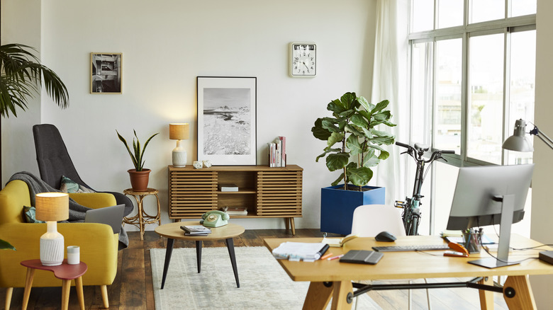 A modern living room with slim furniture, a yellow couch, and a desk,