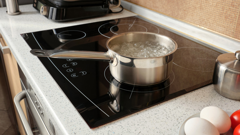 Boiling water in a metal pot on an induction cooker against the background of a kitchen. Cooking at home.