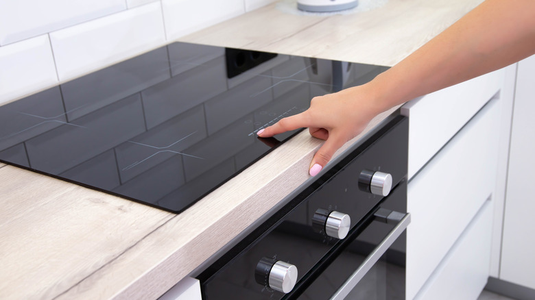 Modern induction hob in the kitchen. A woman's hand sets the heating power of the burner
