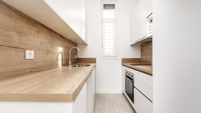 galley style kitchen with white cabinets and wood counters