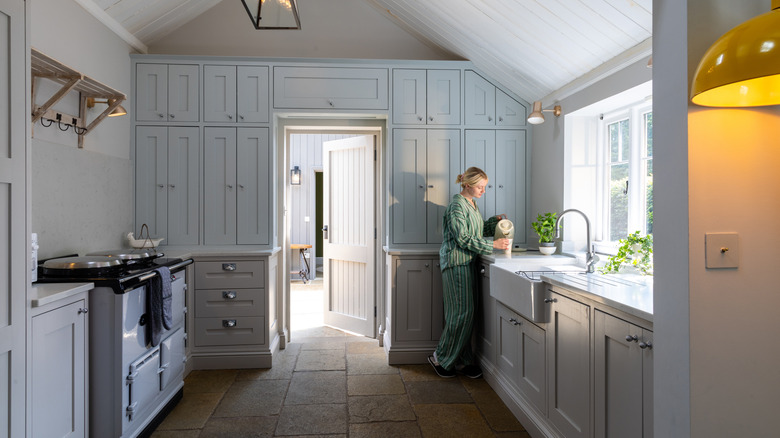 woman standing in kitchen with light blue floor-to-ceiling cabinets