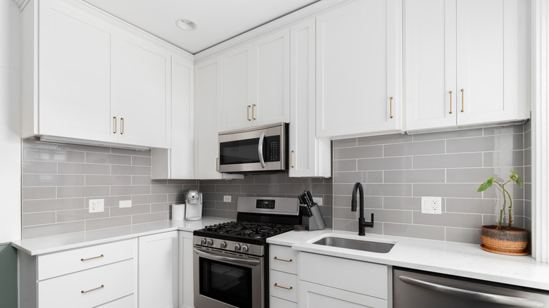 A small, white kitchen with a gray subway tile backsplash, and stainless steel appliances