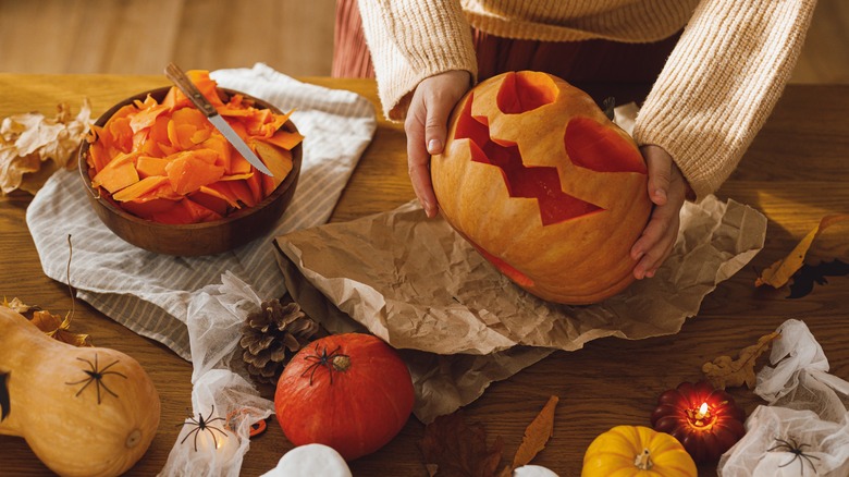 Woman carving a pumpkin on table