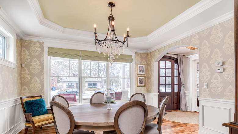 A dining room with wallpaper on the walls and a painted ceiling