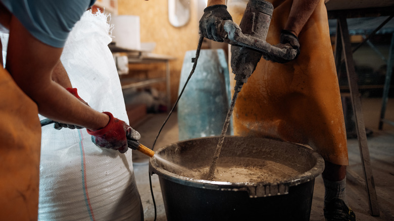 Two people mixing concrete in bucket