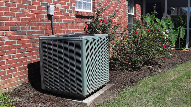 A central air conditioning system outside a red brick home.