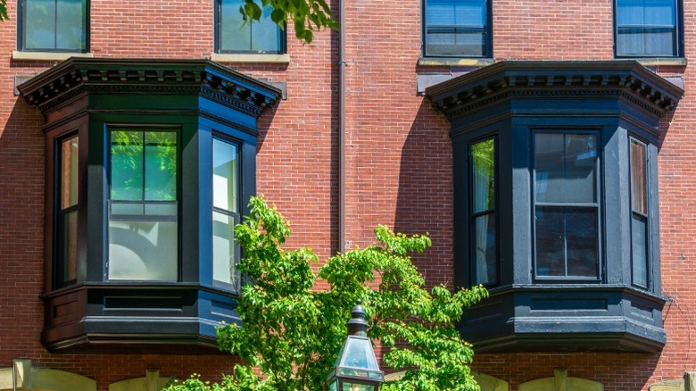 Two ornate black oriel windows on the wide of a brick building