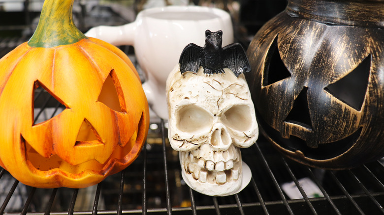 Thrift store shelf with Halloween decorations lie carved pumpkins and skulls.