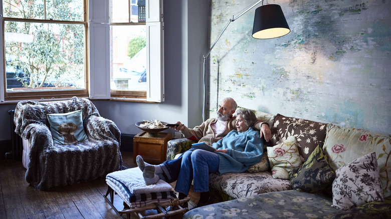 A couple sits in a chintzy floral sofa in a modern living room