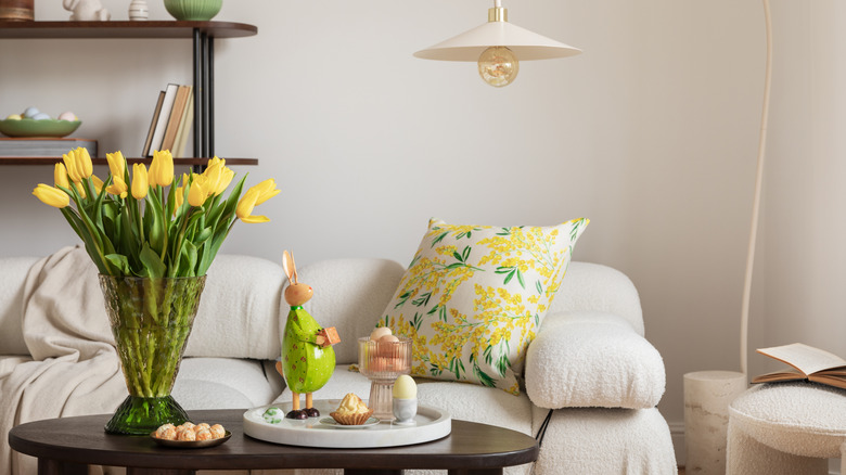 A close-up of a cream sofa with a floral pillow