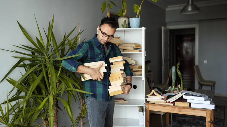 Man holds many books to shelve