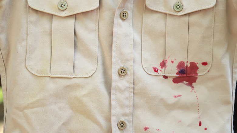 A close-up image of a red wine spill on a buttoned shirt