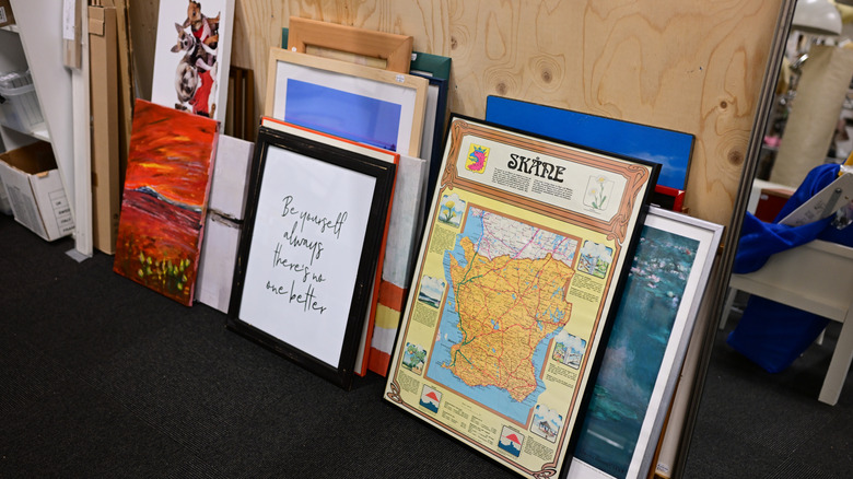 Framed art leaning against a wall in a thrift store