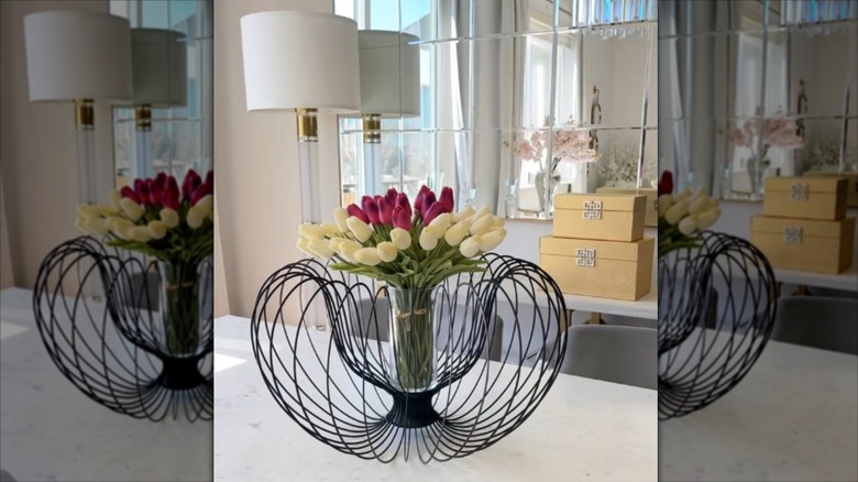 a striking combination of a light fitting, a cylinder vase, and cut flowers