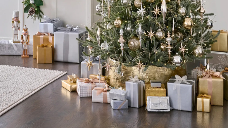 A fully decorated Christmas tree with a metallic gold tree collar at its base