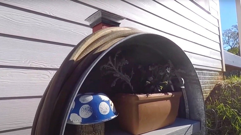 DIY garden hose holder with an LED solar light and decor inside next to a house