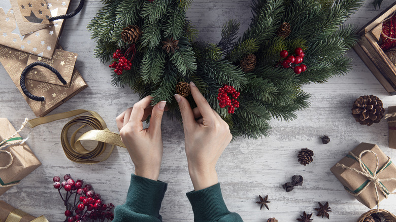 person adding pinecones to their wreath