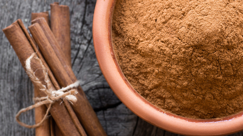 bundle of cinnamon next to bowl of ground cinnamon