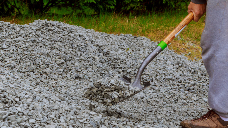 Man shovels gravel from a pile.