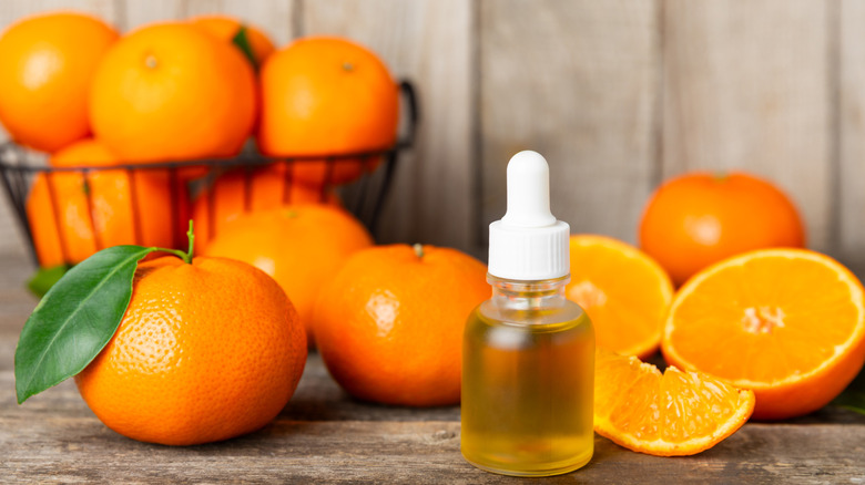 Oranges next to a dropper of orange essential oil
