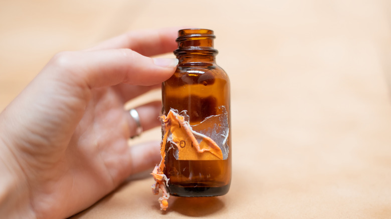 Person holding a bottle with the label partially removed