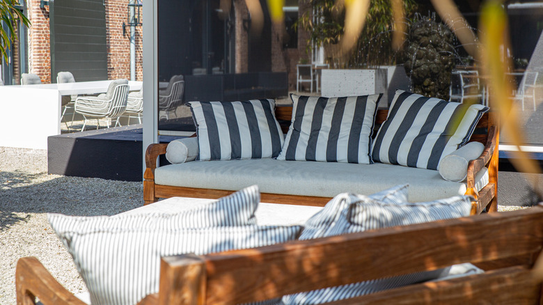 Outdoor wooden patio couches with grey cushions and striped throw pillows