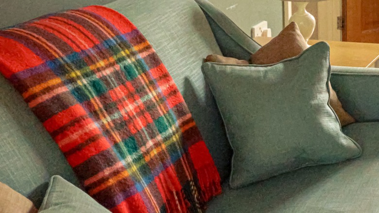 Red and green tartan blanket on green sofa