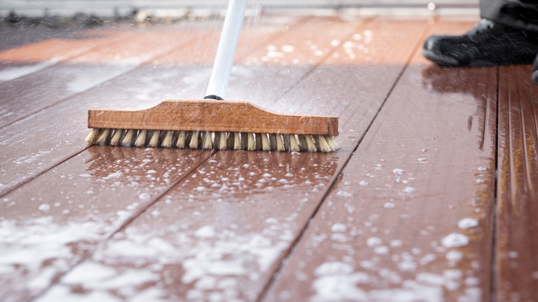 Person cleaning deck floor scrubber