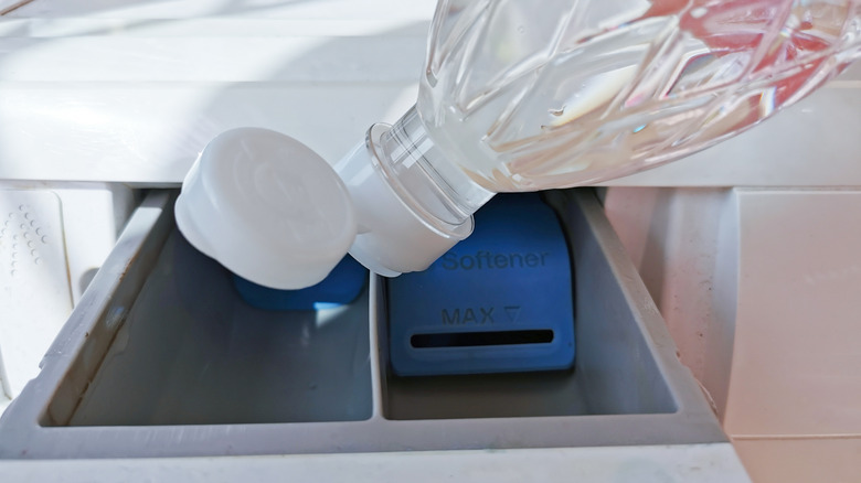 Close up of pouring vinegar in fabric softener compartment