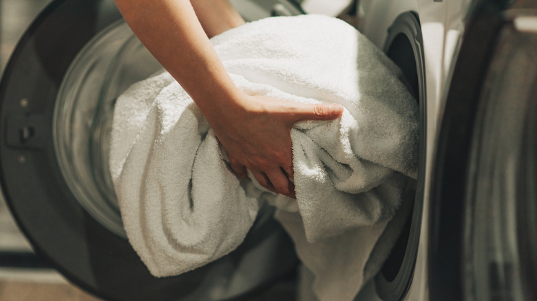 Close up of hands loading the washing machine with towels